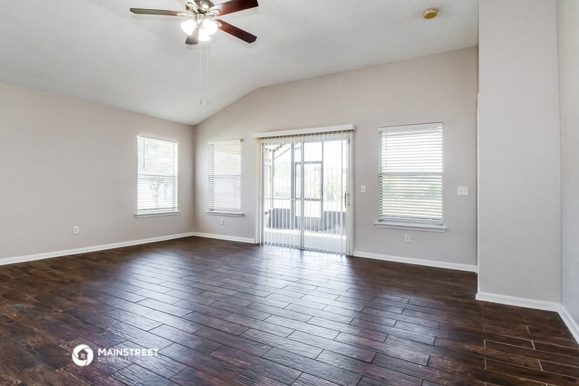an empty living room with wood flooring and a door to a balcony