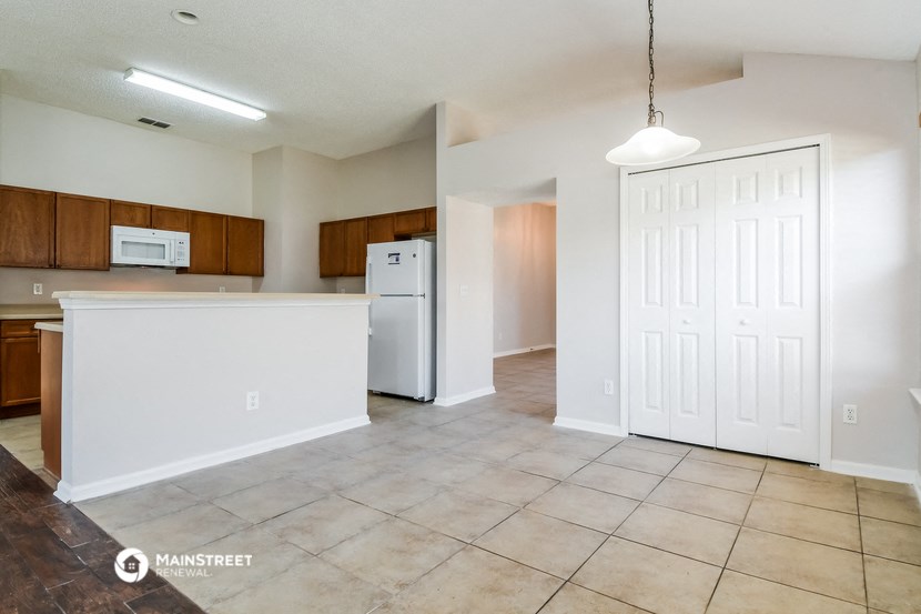 the kitchen and living room of an apartment with a refrigerator and a microwave