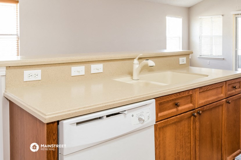 a kitchen with a sink and a dishwasher and wooden cabinets