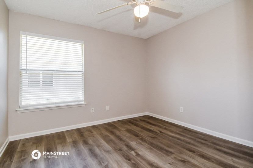 the spacious living room with wood flooring and a ceiling fan