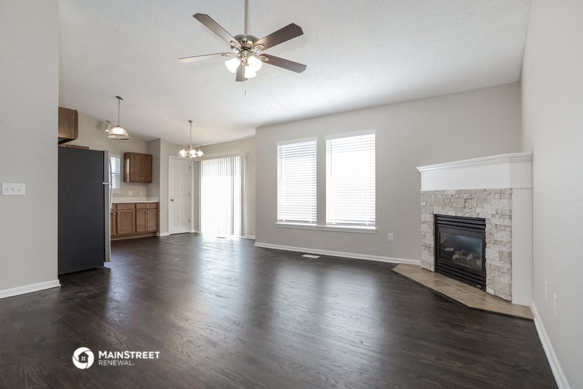 an empty living room with a fireplace and a ceiling fan