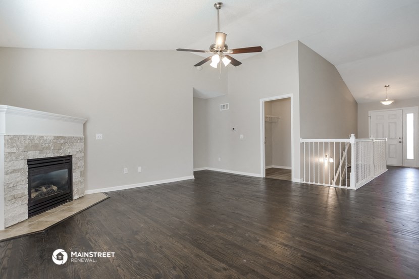 the living room with a fireplace and a ceiling fan