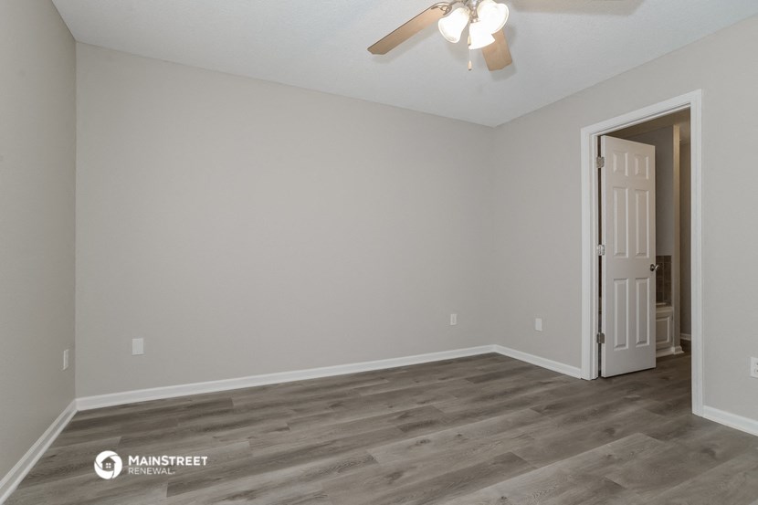 the spacious living room with a ceiling fan and wood flooring