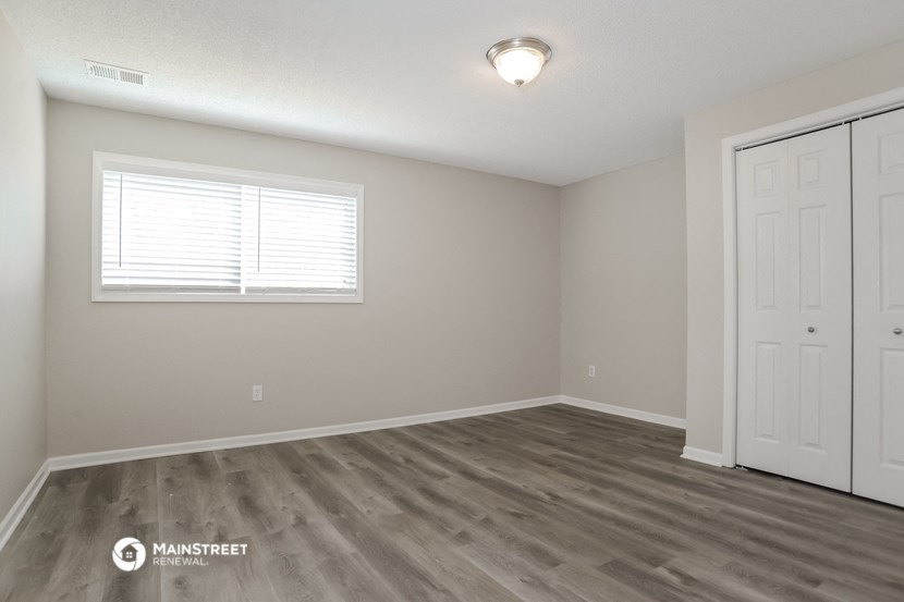 the spacious living room with a white door and a window