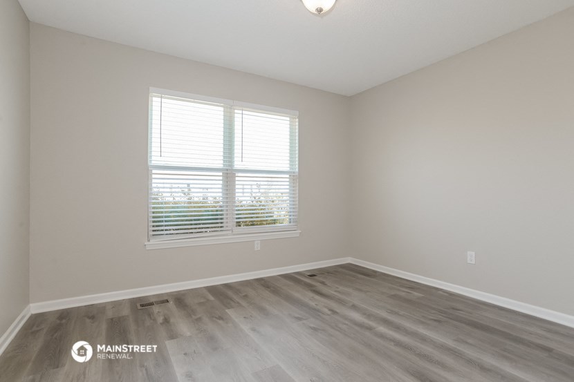 the spacious living room with wood flooring and a window