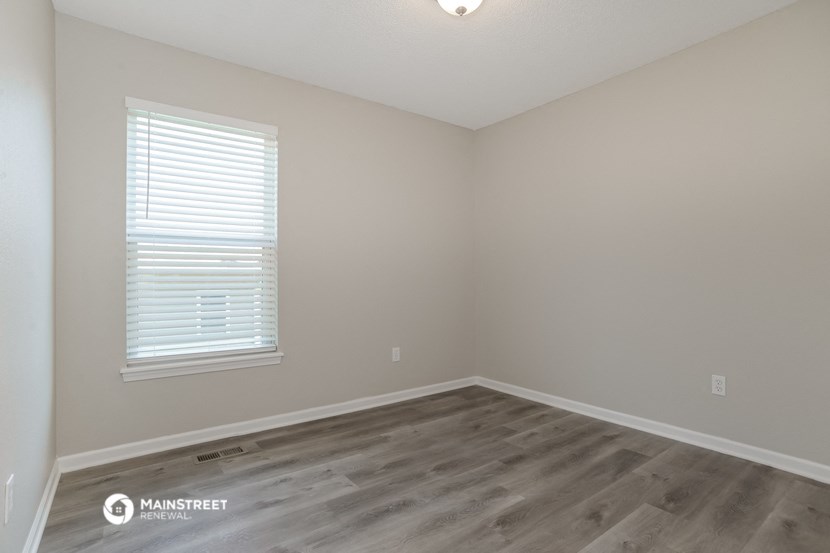 the interior of a bedroom with wood flooring and a window