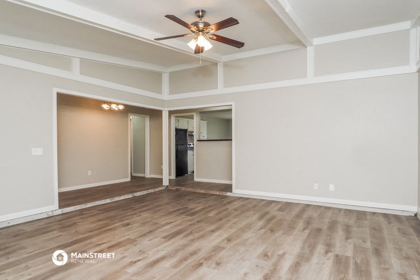 the living room of an empty house with a ceiling fan