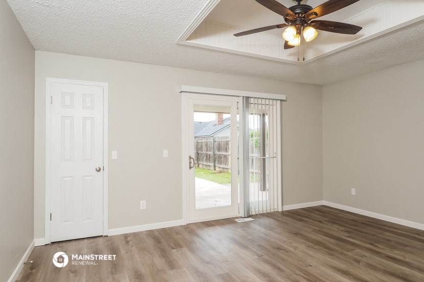 an empty living room with a ceiling fan and a door to a yard
