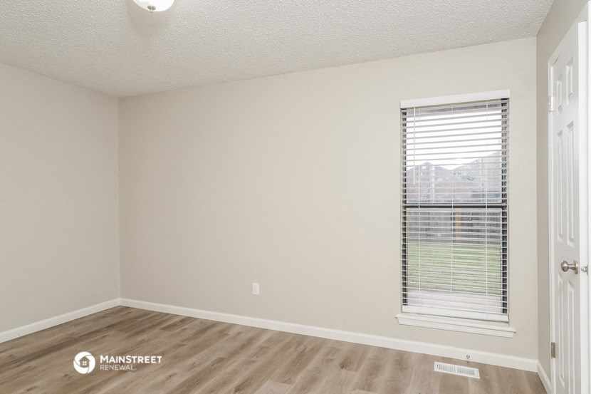 the spacious living room with a window and wood flooring