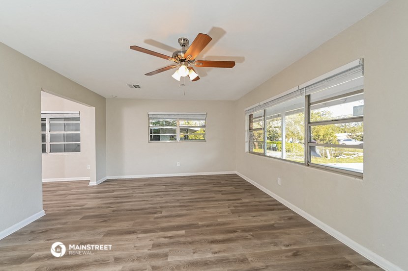 an empty living room with a ceiling fan and windows