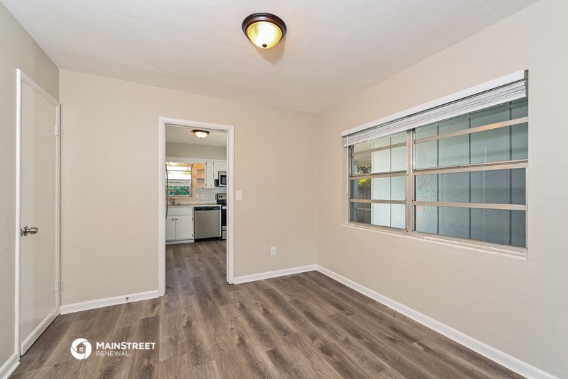 a living room with a window and a door to a kitchen