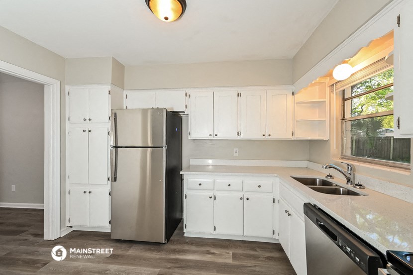 a kitchen with white cabinets and a stainless steel refrigerator