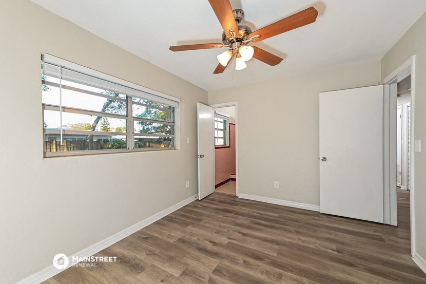 a living room with a large window and a ceiling fan
