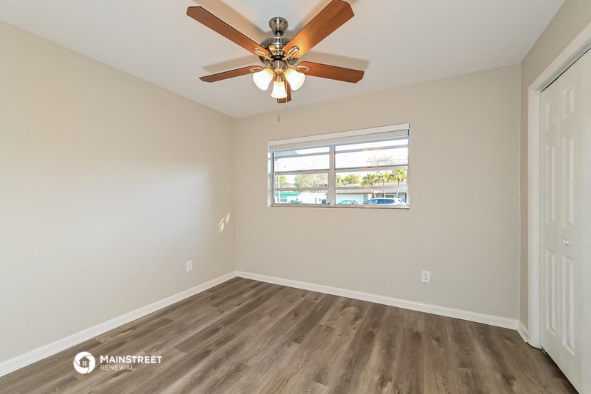 the spacious living room with ceiling fan and wood flooring