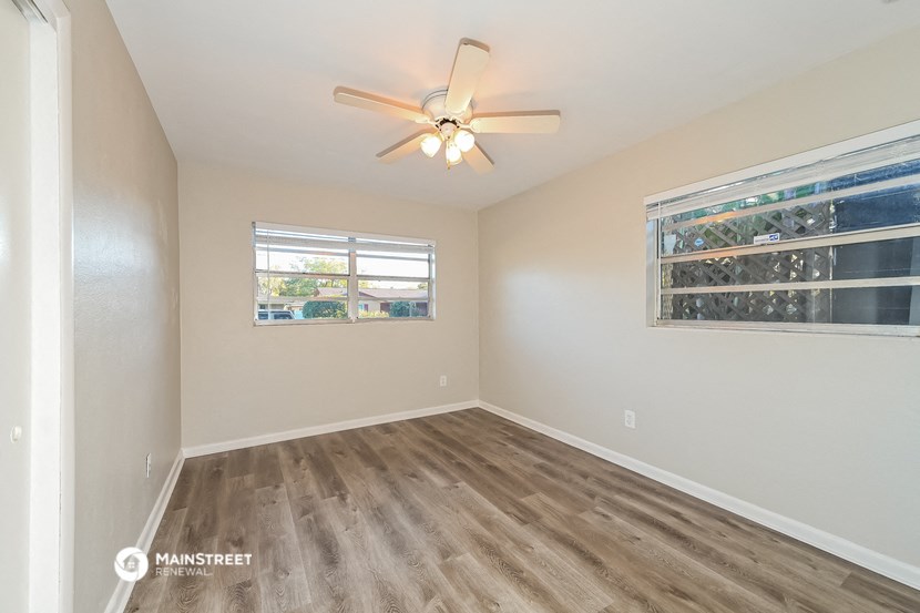 the living room of an empty house with a window and a ceiling fan
