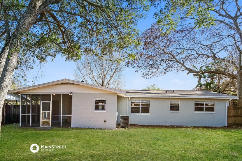 a small white house with a yard and trees