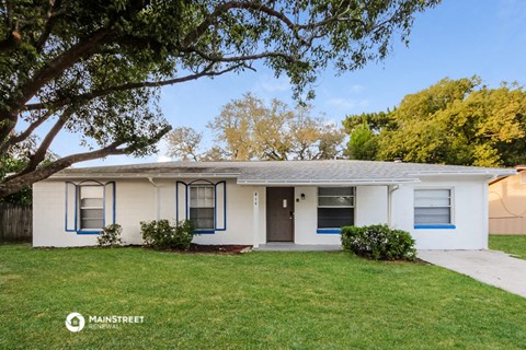 a small white house with a yard and a tree