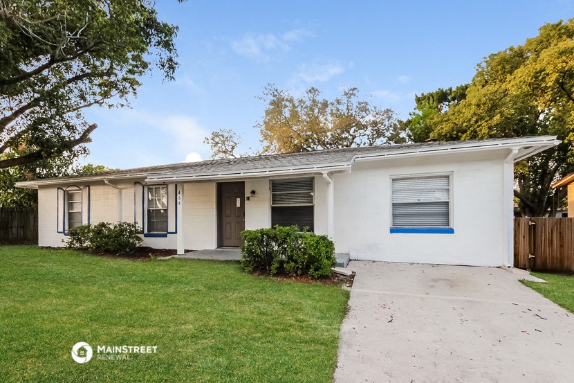 a small white house with a sidewalk and grass