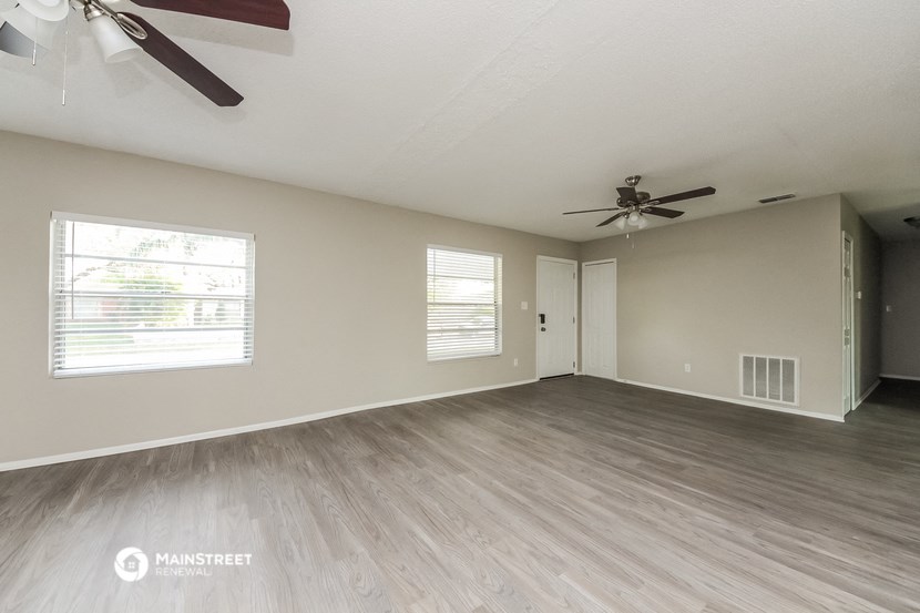 an empty living room with wood floors and a ceiling fan