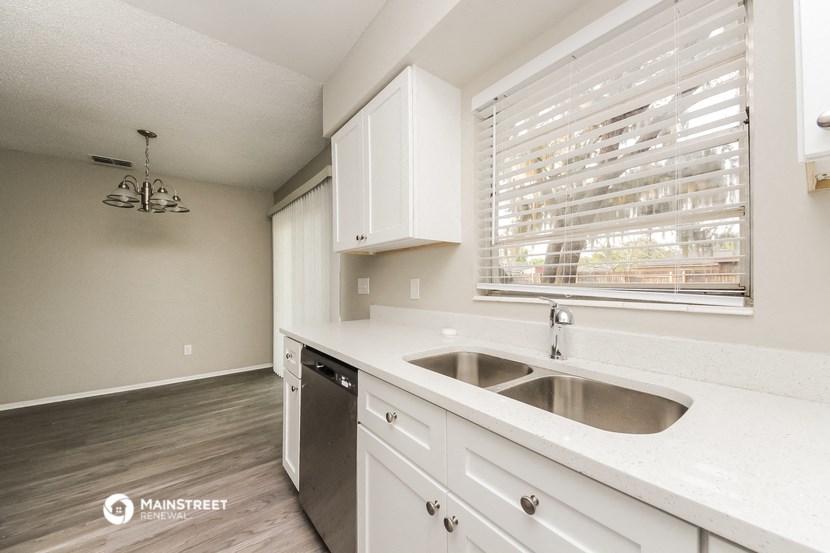 a kitchen with white cabinets and a sink and a window