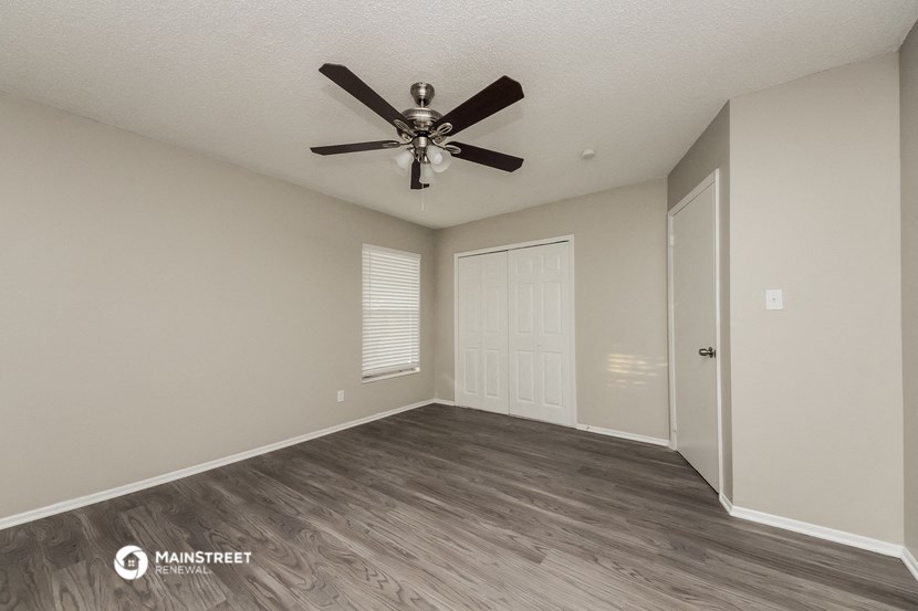 the spacious living room with a ceiling fan