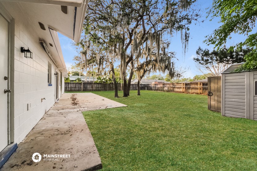 a backyard with grass and trees and a white house