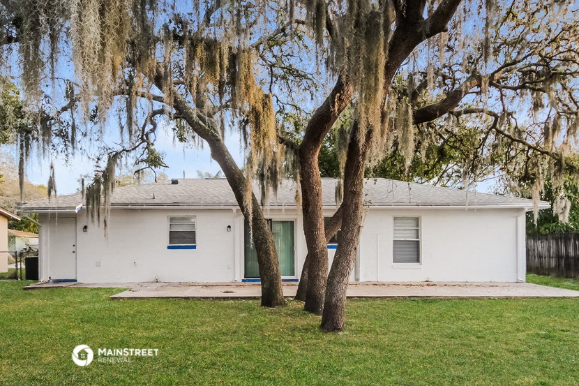 a white house with moss covered trees in front of it