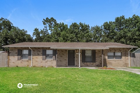 a brick house with a grassy yard and trees