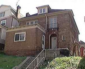 A brown brick house with a white door and a window.