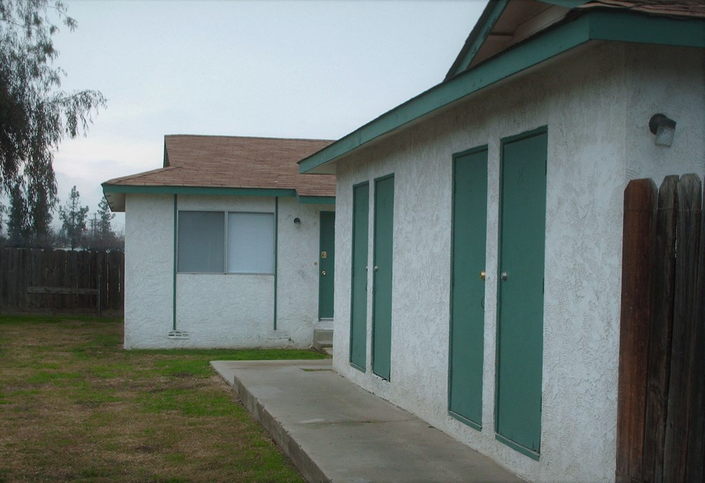 the outside of a white house with green doors
