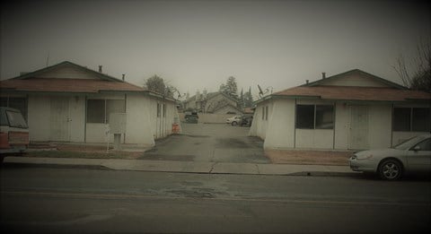 an empty street with two buildings and a car on it