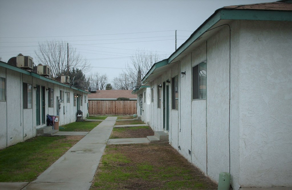 a row of white buildings with green roofs and a sidewalk