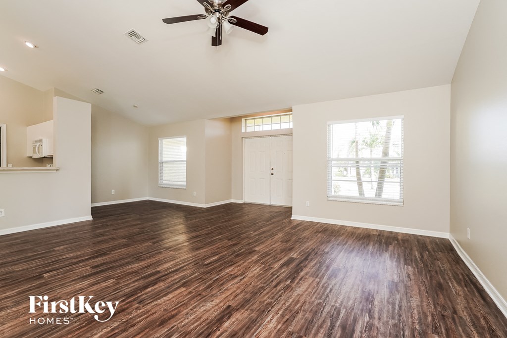 A spacious room with wooden flooring and a ceiling fan.