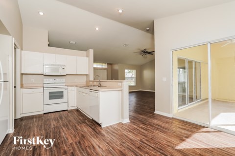 A kitchen with white appliances and wooden floors.