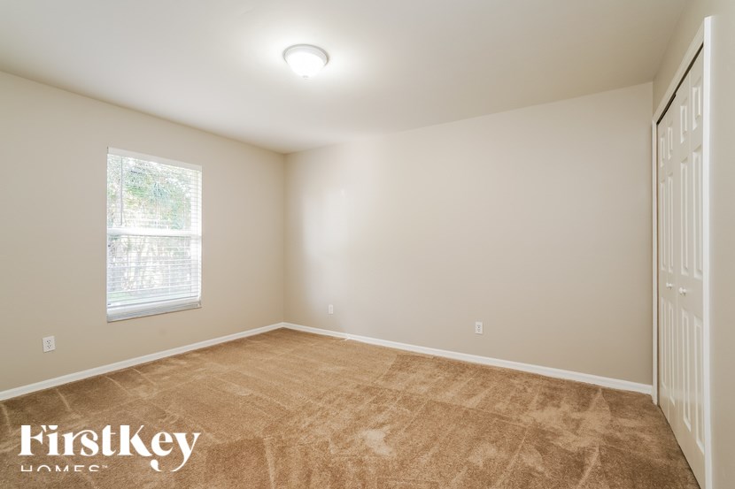 A room with a carpeted floor and a window with a view of trees.