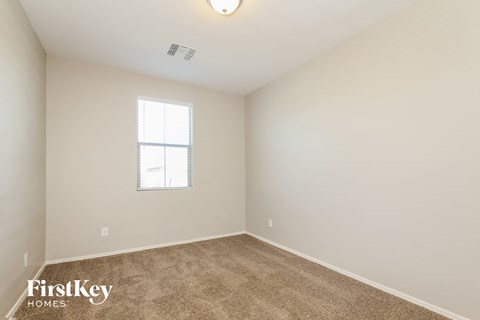a bedroom with white walls and carpet and a window