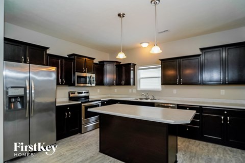 a kitchen with black cabinets and white countertops and stainless steel appliances