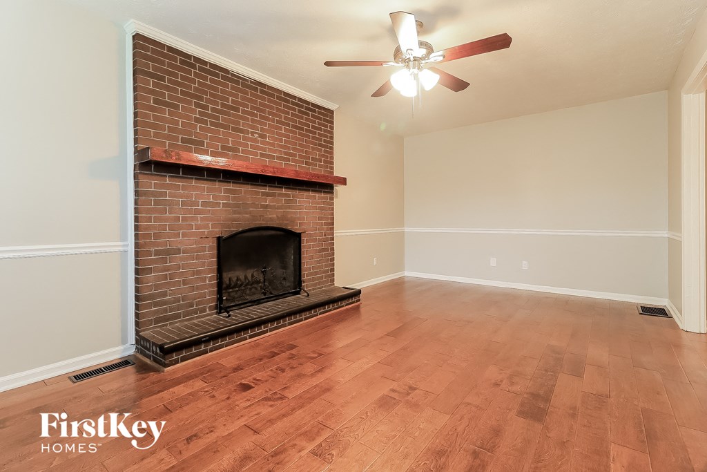 a living room with a brick fireplace and a wooden floor