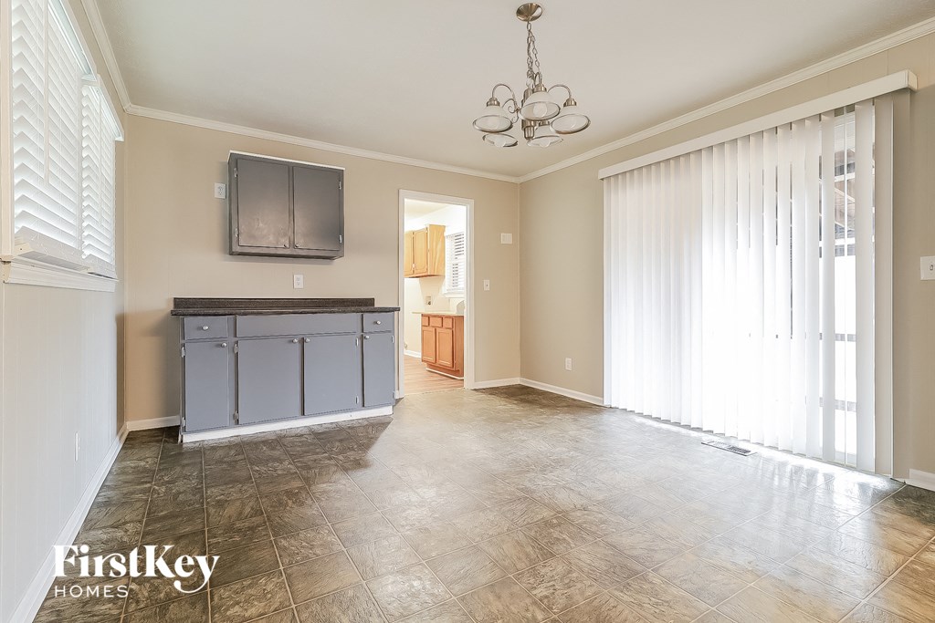 an empty living room with a kitchen and sliding glass doors
