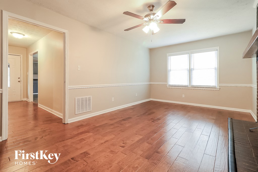 an empty living room with wood floors and a ceiling fan
