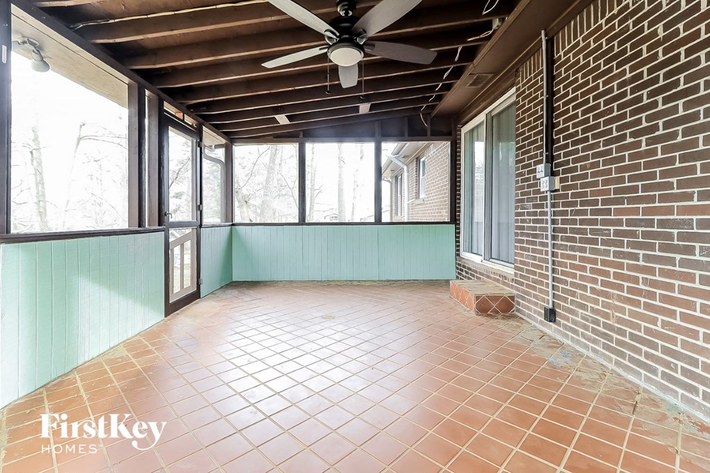 an empty living room with a brick wall and a ceiling fan