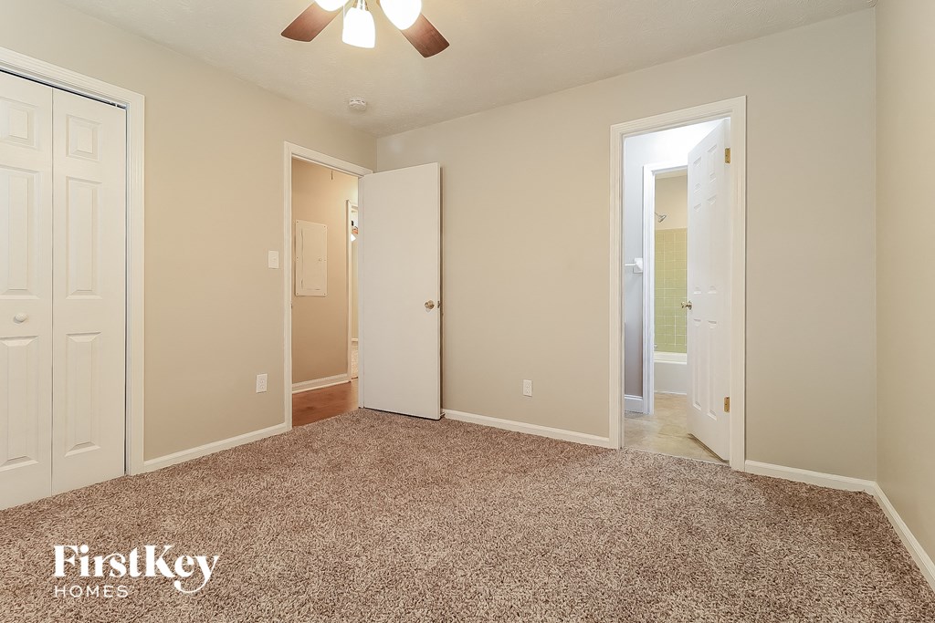 a bedroom with a carpeted floor and a door to a bathroom