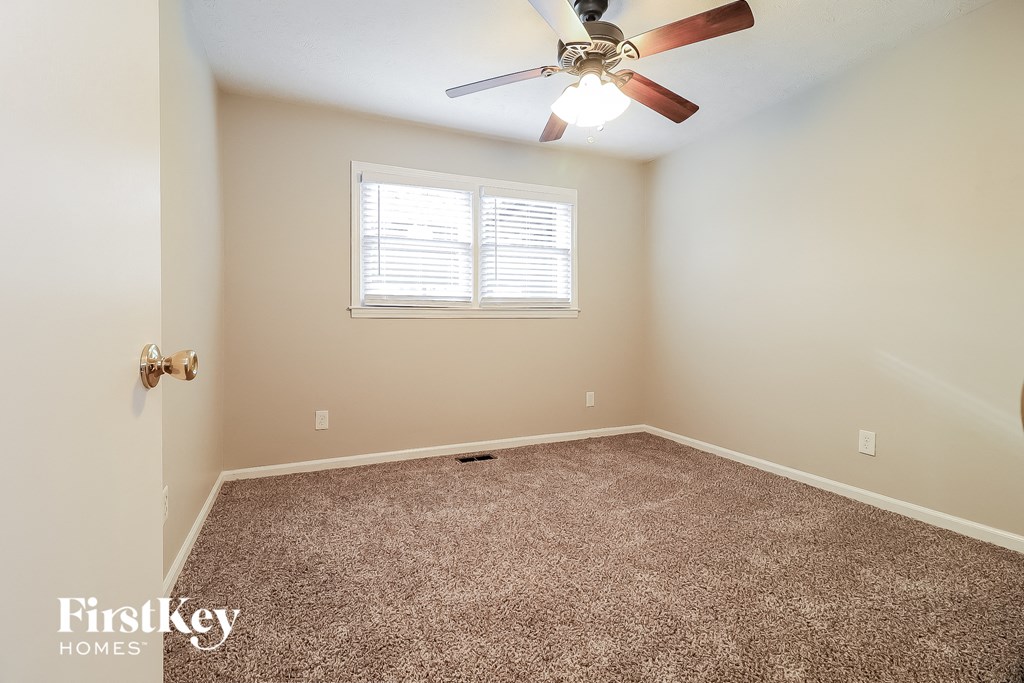 an empty room with a ceiling fan and a window