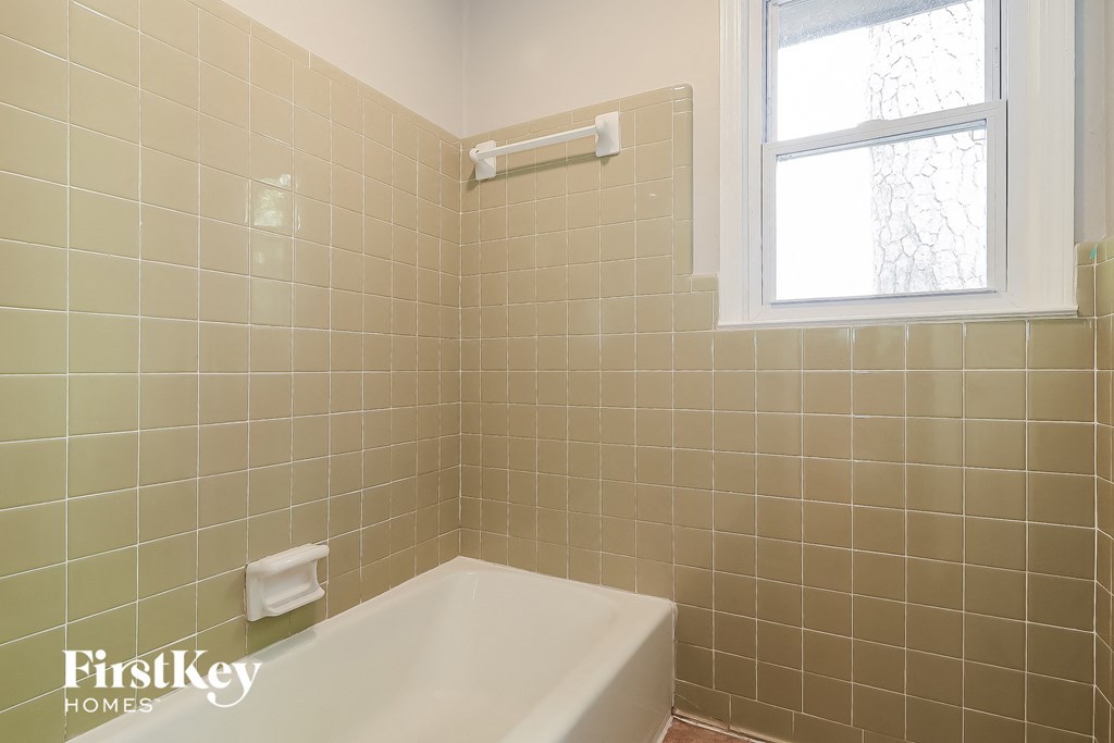 a tiled bathroom with a tub and a window
