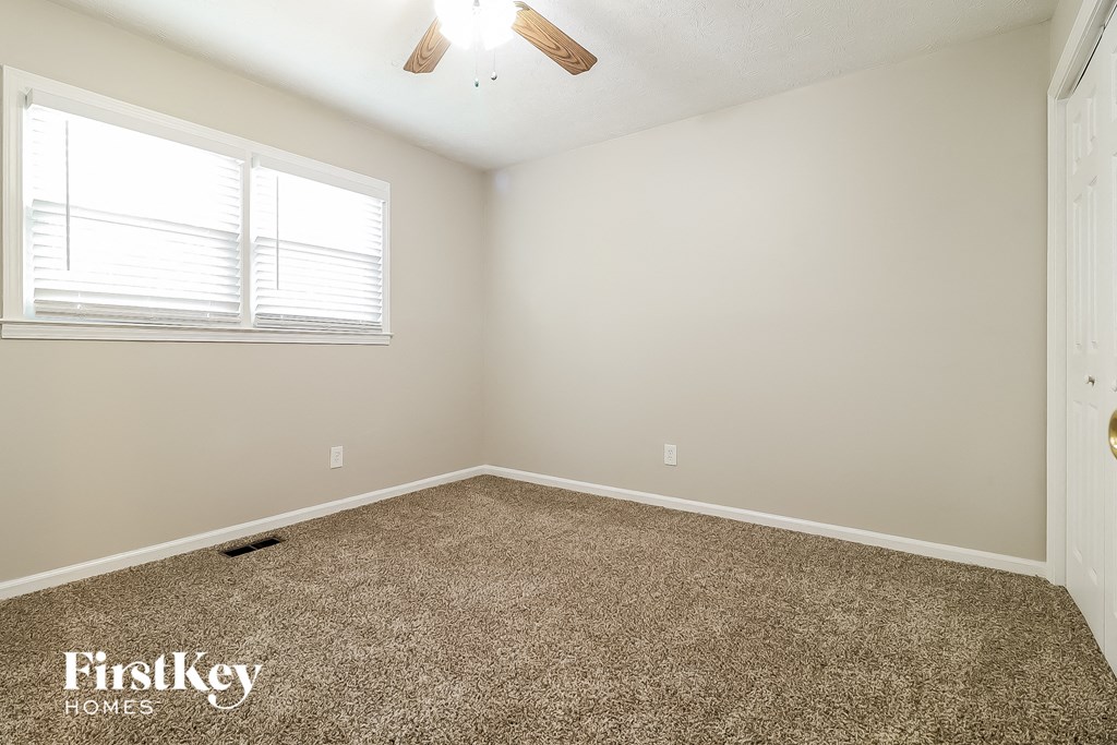 the spacious bedroom with carpeted flooring and a window
