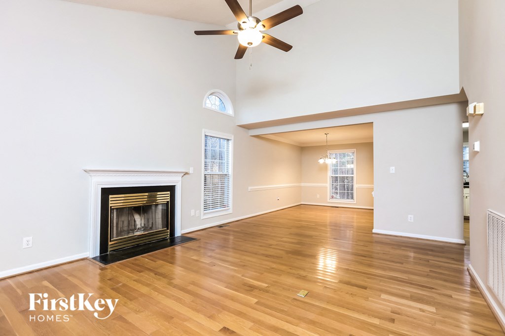 A spacious living room with a fireplace and a ceiling fan.