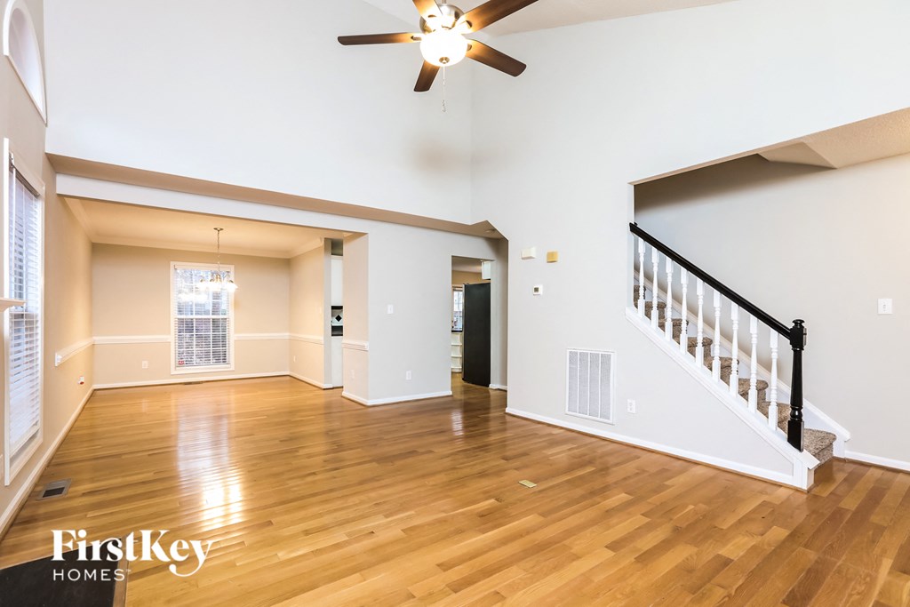 A spacious living room with a wood floor and a ceiling fan.