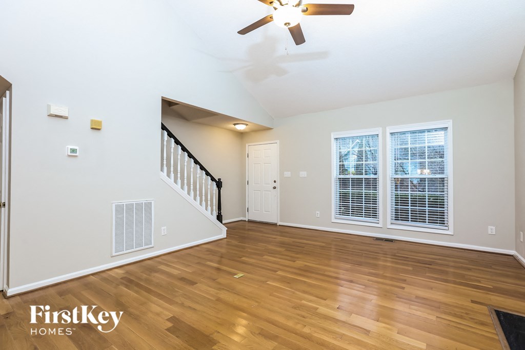 A spacious room with wooden floors and a ceiling fan.