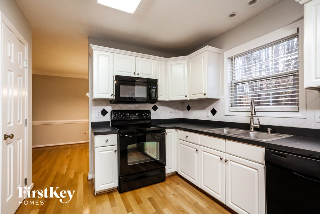 A kitchen with white cabinets and black appliances.