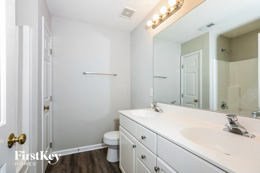 A bathroom with a white sink and a mirror with lights on it.